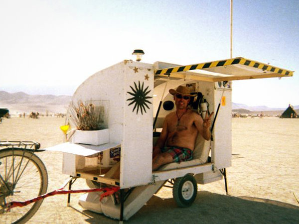 grijnzende man in witte fietscaravan