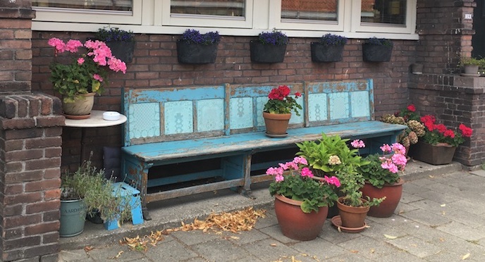 Mooie turqoise geschilderde houten bank met geraniums in potten in de Beemsterstraat.