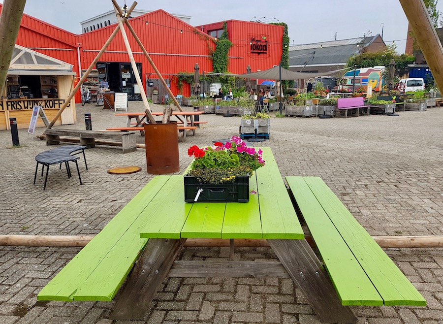 Groene picknichtafel voor rood gebouw met houten plantenbakken