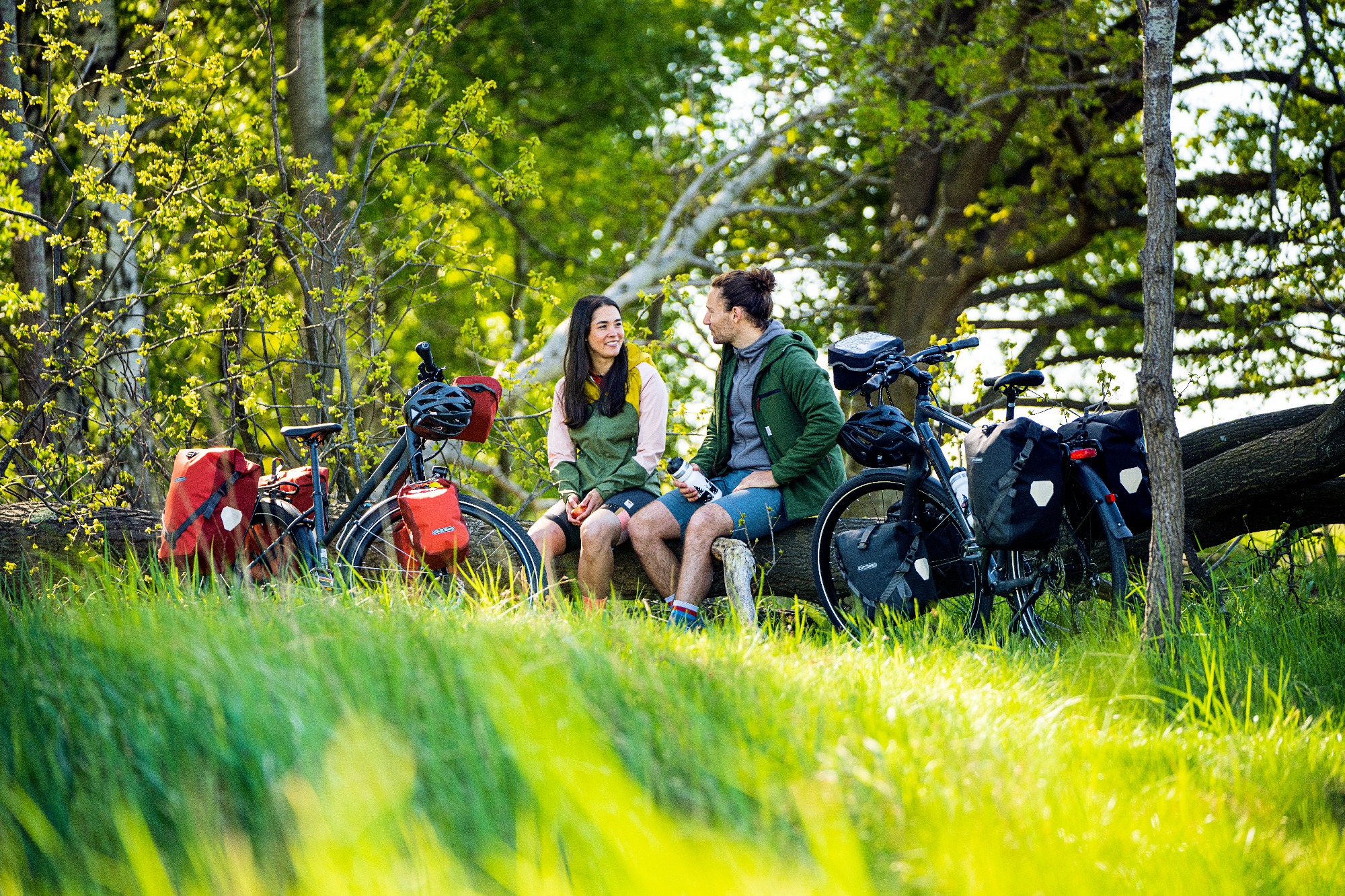 Vakantieifetsers die uitrusten op een bankje, beide fietsen met volledige Ortlieb tassenset.
