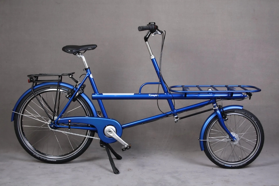 Robuuste blauwe rechtop zitfiets met groot transportrek voorop waar vaak een grote plastic bak van de bouwmarkt op wordt bevestigd.