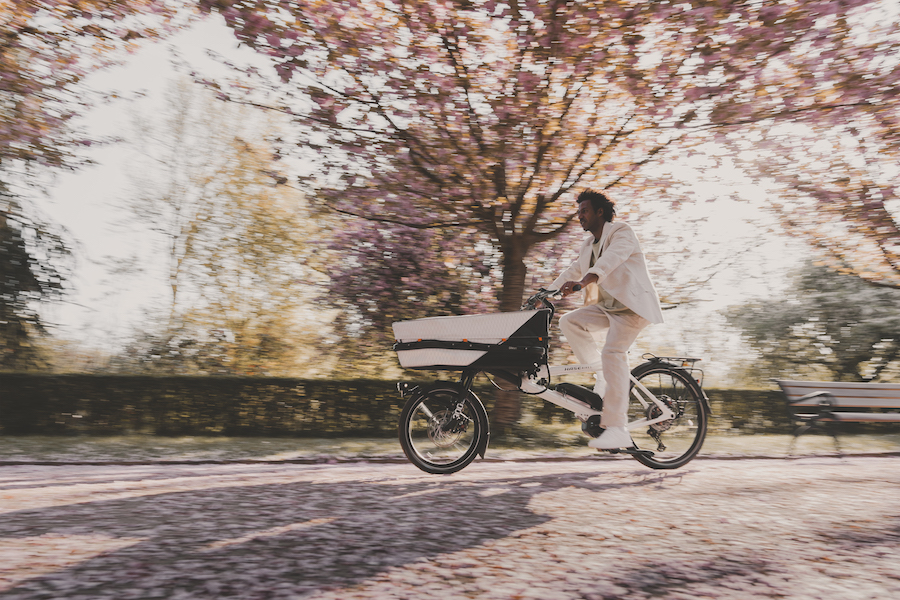 Man in wit pak fiets met tweewielige witte Gravit Dust langs boom