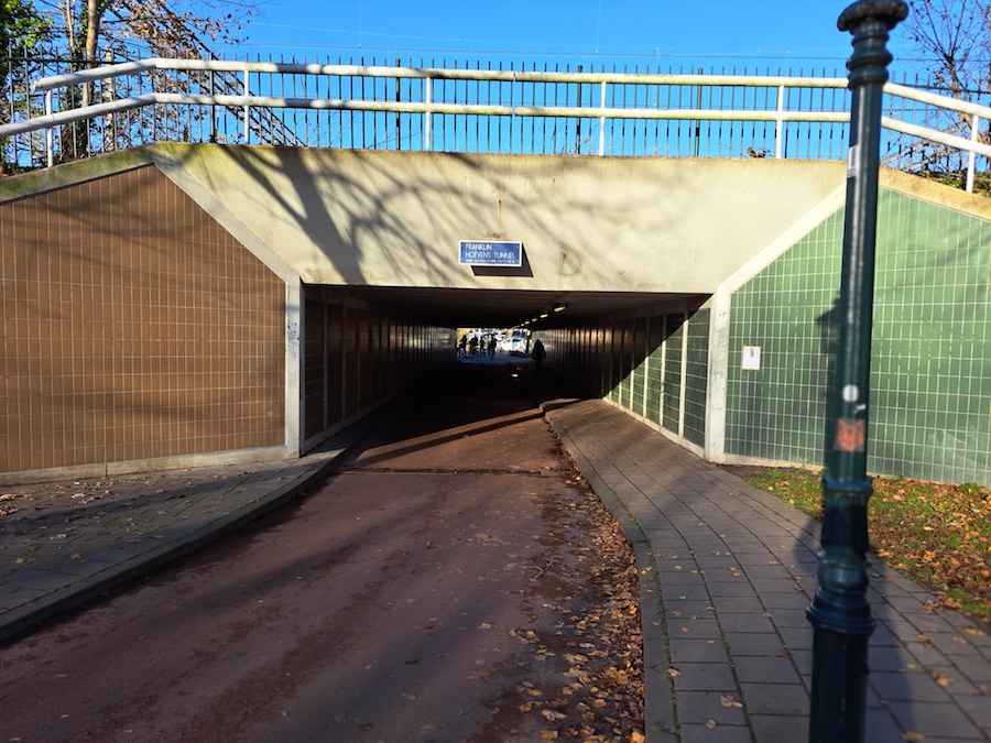 Fietstunnel met in het midden bovenaan de tunnel een blauw naambordje.