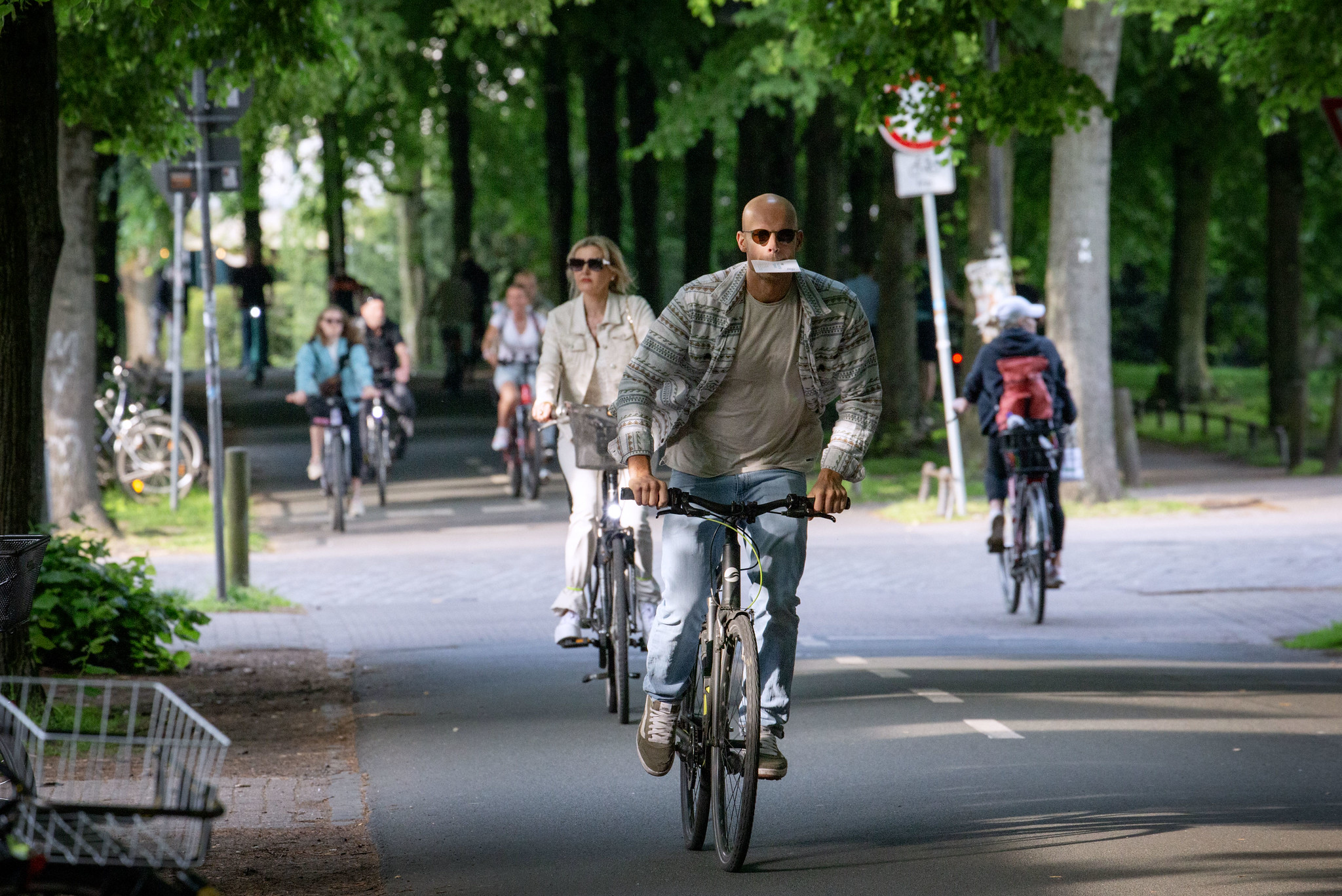 Fietser met envelop in de mond fietst over fietspad met rondom groen