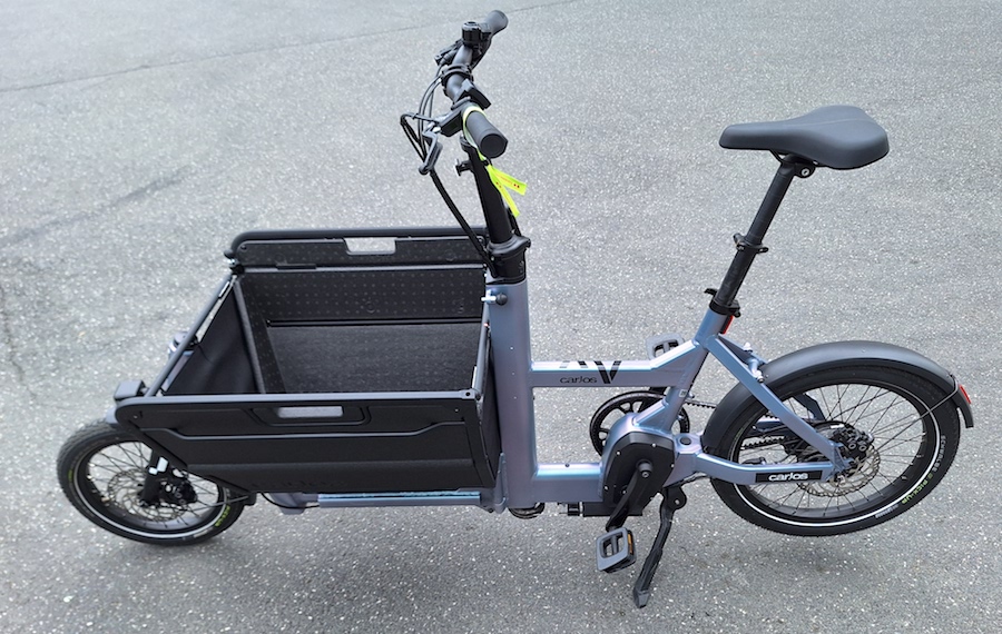 Lila bakfiets met een bak die eruit ziet alsof hij van karton is gemaakt.