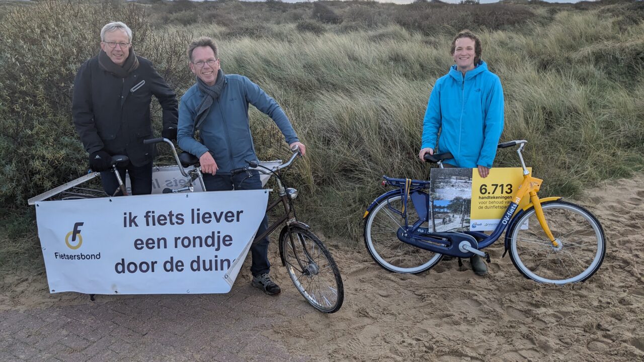 Drie mannen met spandoek in de duinen: 'Ik fiets liever een rondje door de duinen'.