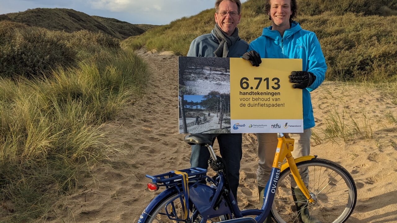 Ross Goorden en Marc v/d Berg van de Fietsersbond poseren met het petitiebord Behoud de fietspaden in de Noord-Hollandse duinen