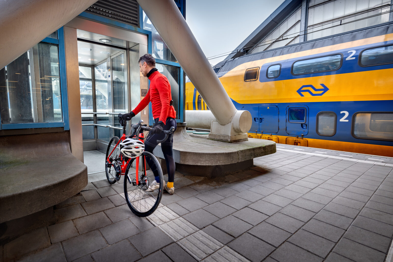 Fietser met racefiets stapt in lift op station Amsterdam Sloterdijk.