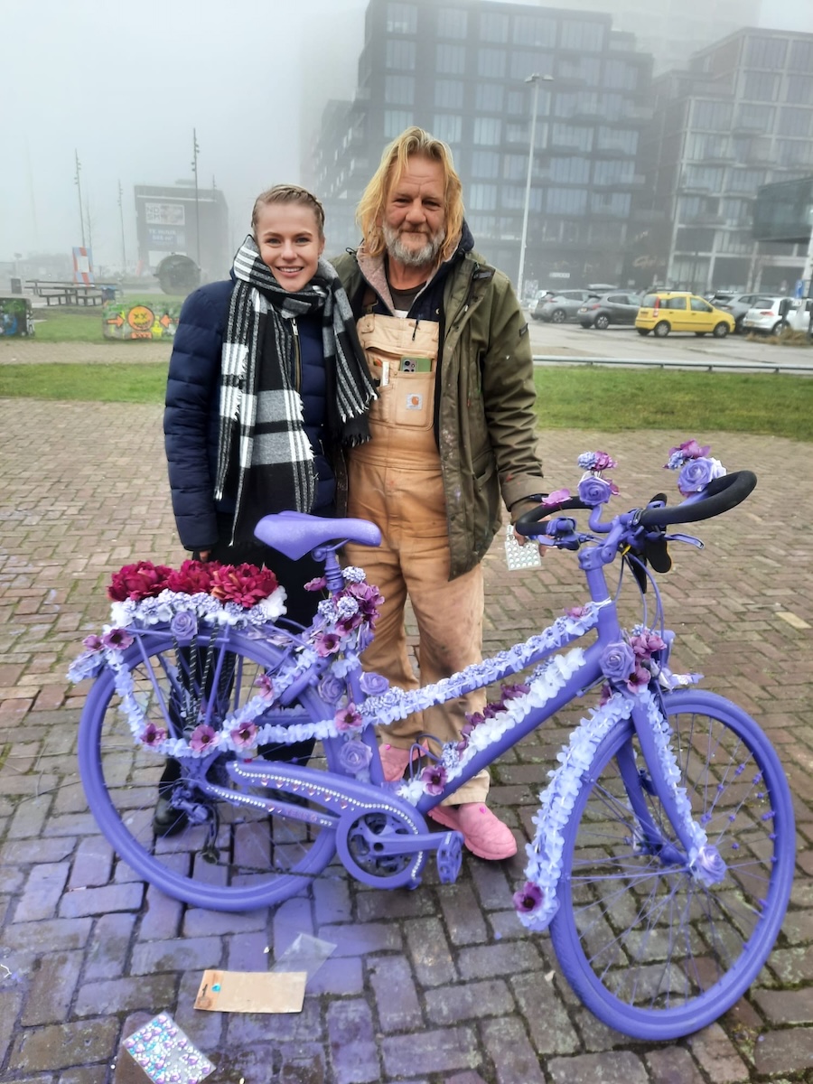 Jonge vrouw en man met paard bij een paarse fiets met bloemen.