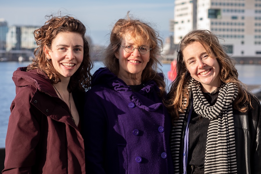 Drie vrouwen in winterjassen voor het IJ in Amsterdam.