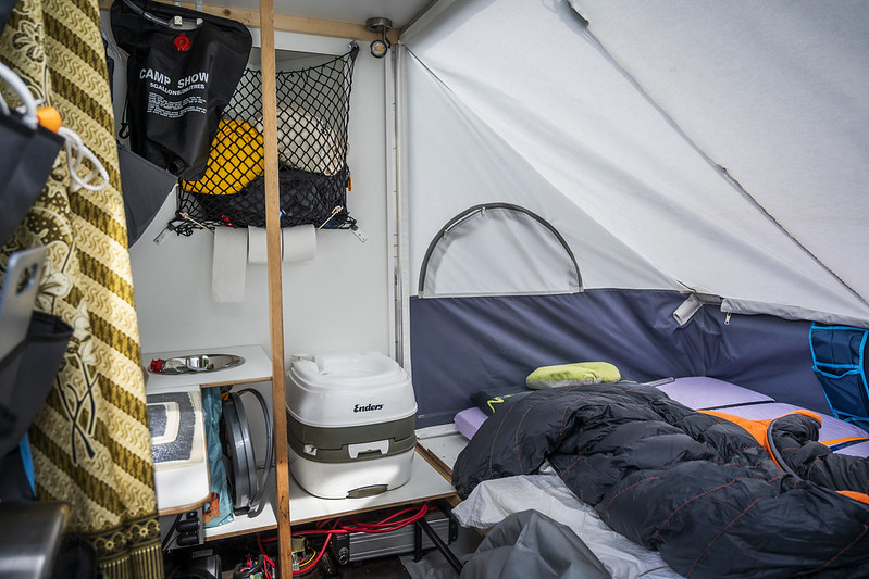 Slaapgedeelte, klein gootsteentje en een handdoek in de fietscaravan.