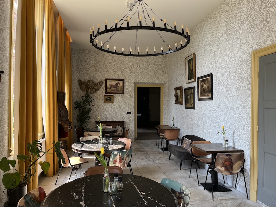 Ruimte met schilderijen van paarden aan de muur op bloemenbehang met moderne kroonluchter.