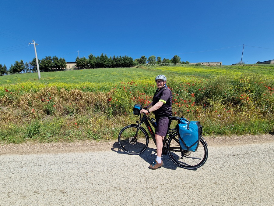 Nies staat met helm op bij zijn vakantiefiets met fietstassen achterop.