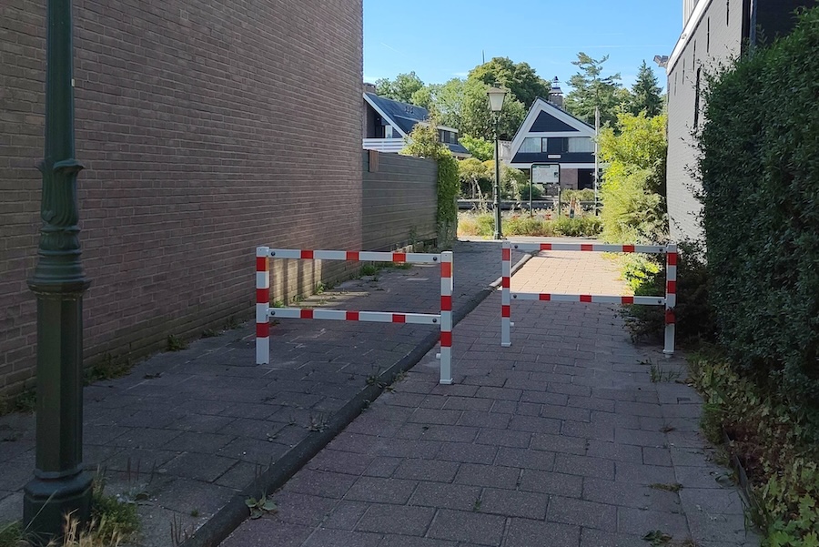 rood/witte hekjes op fietspad tussen twee muren in Leiderdorp.