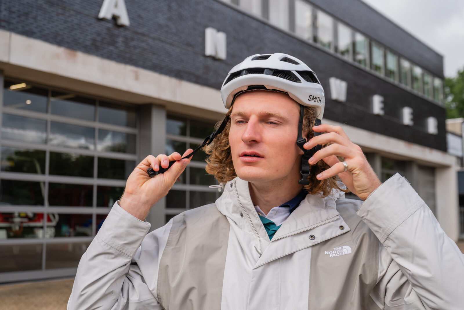 Fietser die jas van The North Face draagt maakt helm vast.