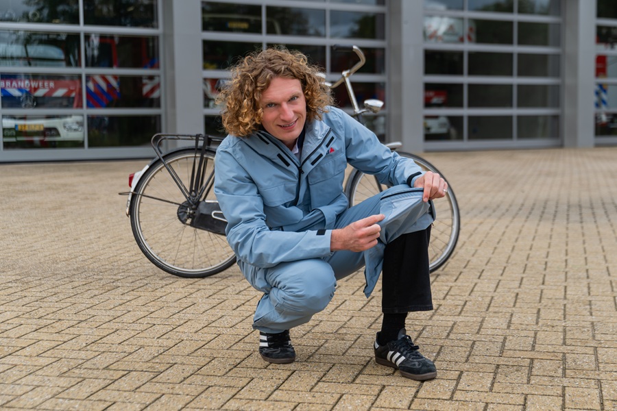 Fietser in blauw regenpak laat rits van regenbroek zien.