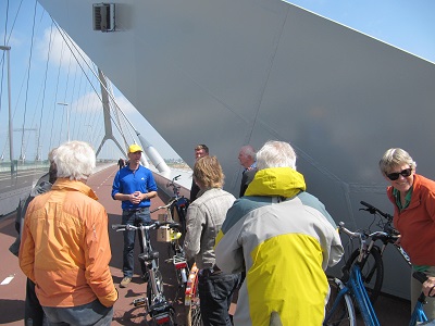 Groep fietsers staat stil en luistert naar uitleg op fietspad brug Oversteek